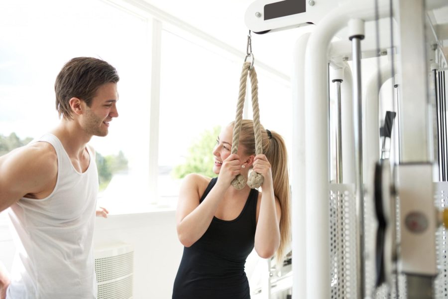 Девушка мило беседует с парнем в тренажерном зале во время выполнения упражнения