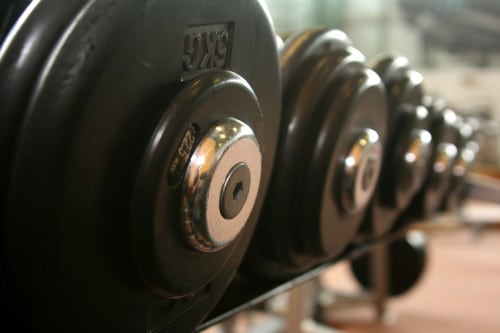 Weights in a rack. Bodybuilding can be severely hindered if you suffer from Low T. Learn more.