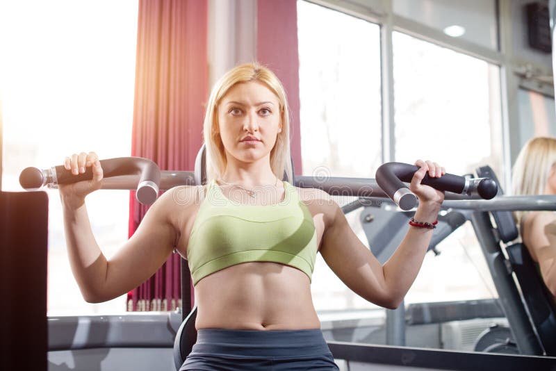 Arms exercise in gym, blonde girl. Arms exercise in gym, blonde young girl royalty free stock image