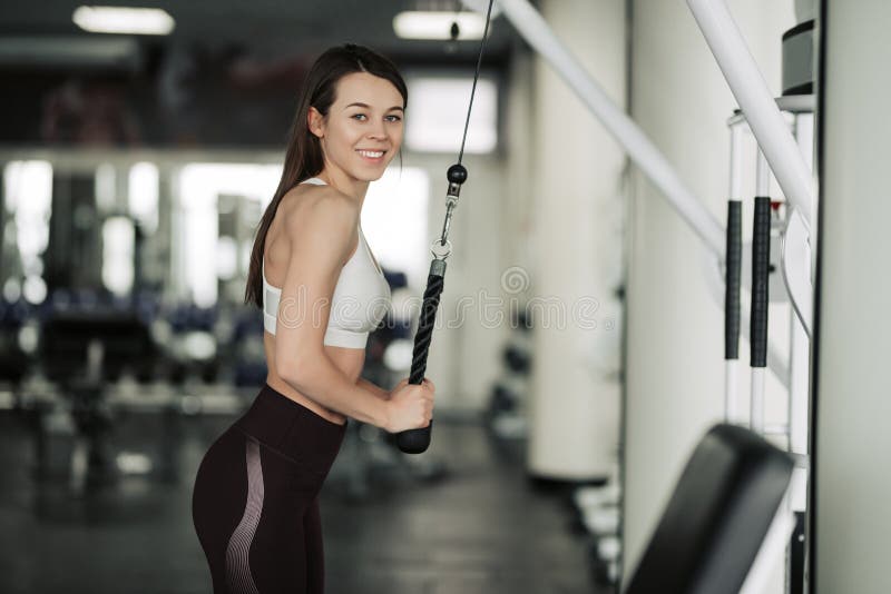 Athlete girl in sportswear working out and training her arms and shoulders with exercise machine in gym.  royalty free stock photo