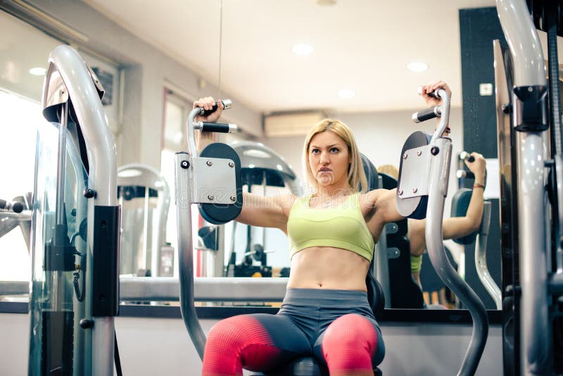 Attractive woman exercising at gym, arms workout. Blonde girl royalty free stock image