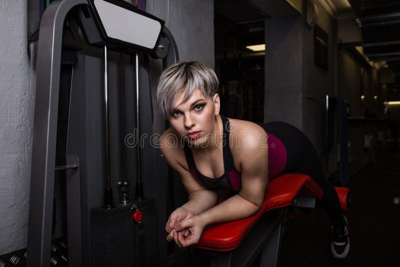 Beautiful sport girl is engaged on a simulator in the gym. Pretty girl with the beautiful tightened figure. Fitness girl royalty free stock image