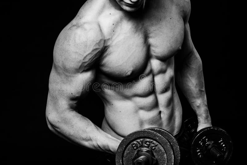 Black and white close-up of handsome power athletic mans hand stomach abs in training pumping up muscles with dumbbells royalty free stock images