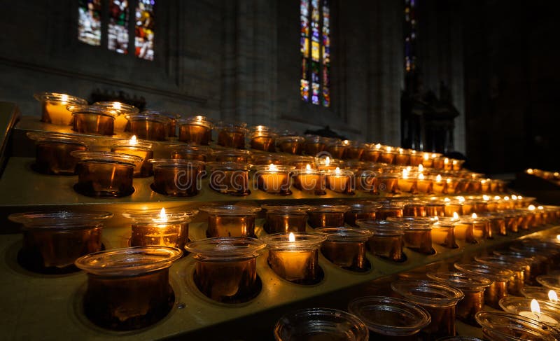 Candles burn inside church, close view of candles in dark cathedral interior royalty free stock photos