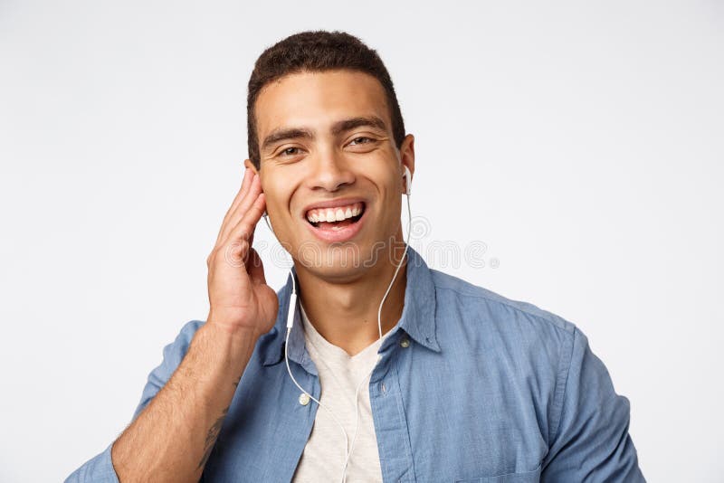 Close-up cheerful, happy laughing young handsome man in casual outfit, put headphones, touch earphone and smiling as royalty free stock photography