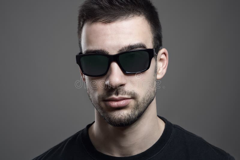Close up headshot of serious young handsome man wearing sunglasses royalty free stock image