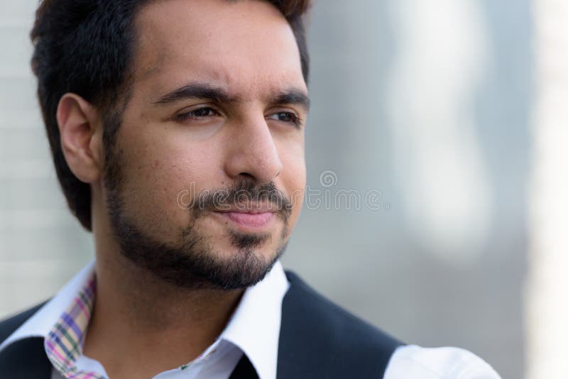 Close up of young handsome Indian man thinking outdoors in the c royalty free stock image
