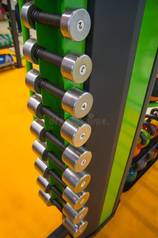 Dumbbells in gym, close up many on horizontal rack in sport fitness centre. stock images