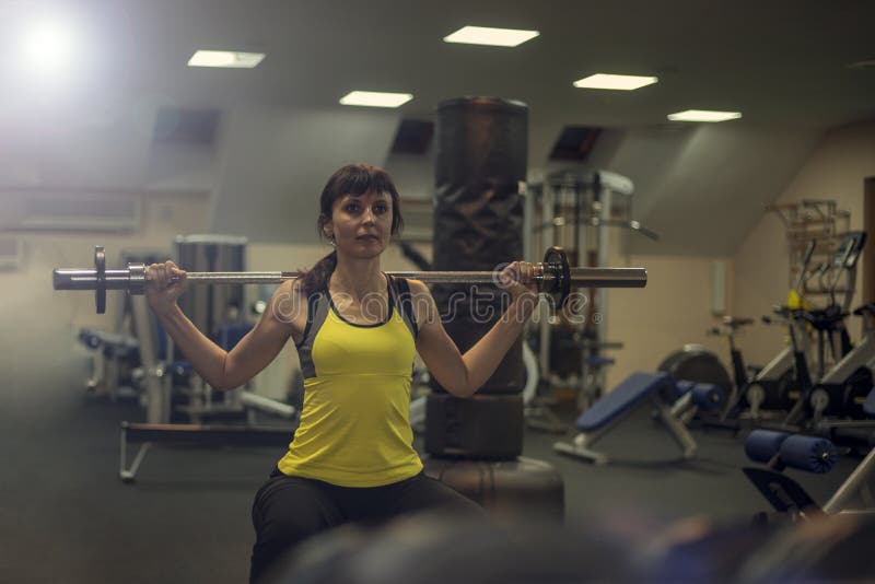 Fitness exercises, a woman performs an exercise bar bench press on the shoulders.  stock photography