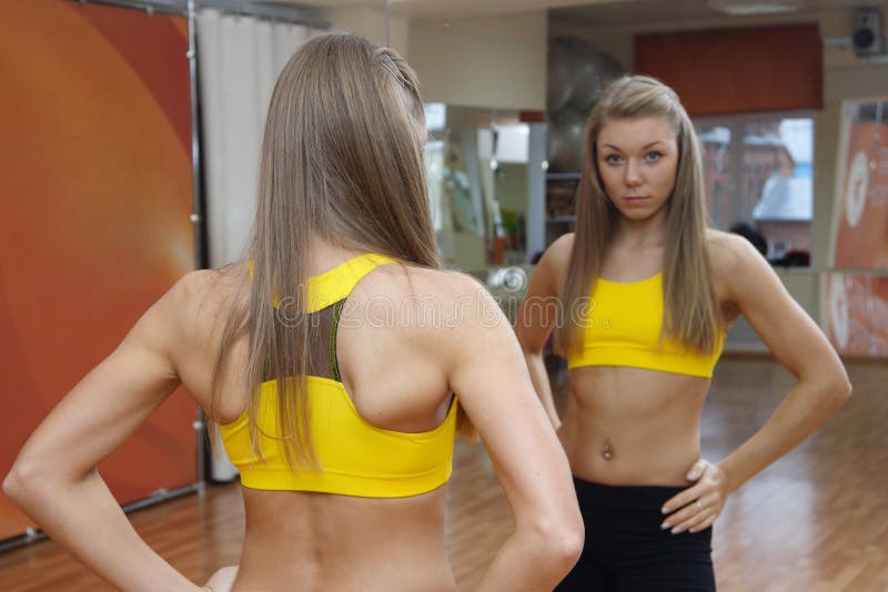 Girl looking in mirror gym indoors. Beautiful Girl in Fitness Gym Photoshoot. More images of this models you can find in my portfolio stock images
