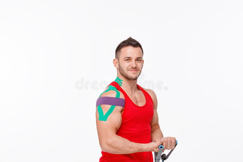 Kinesiology taping. Kinesiology tape on patient knee and shoulder. Young male athlete doing exercises with expender. Post traumatic rehabilitation, sport stock image