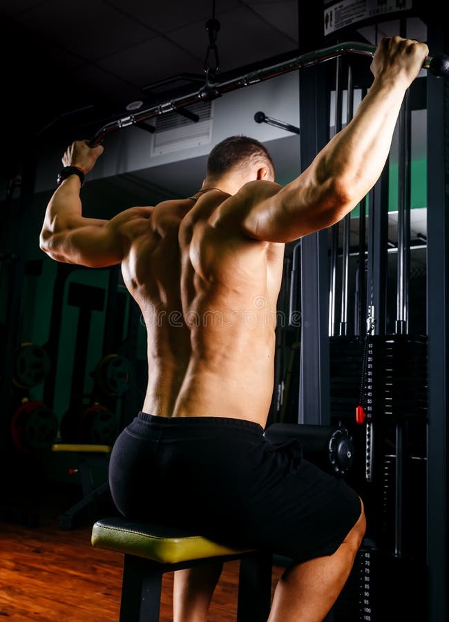 Power athletic guy bodybuilder, execute exercise with gym apparatus, on broadest muscle of back. Very power athletic guy bodybuilder, execute exercise with gym royalty free stock images