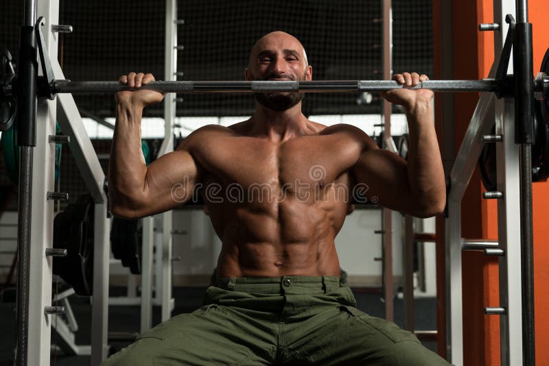 Shoulder Exercises On A Smith Machine. Mature Man Doing Shoulder Exercises In The Gym royalty free stock photos