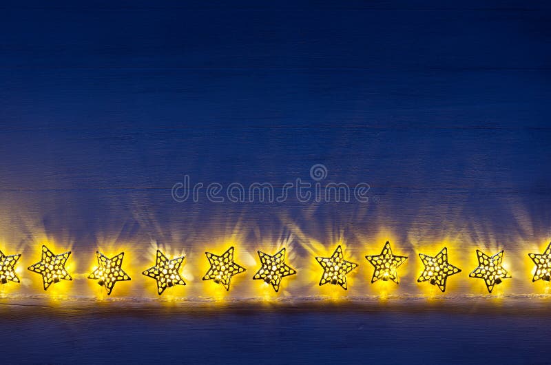 Sparkling lights stars burn on dark blue wood board. royalty free stock photography