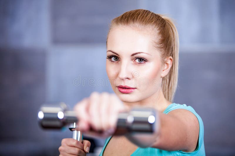 Strong blonde woman weightlifting at the gym, doing shoulders exercise. Strong blonde caucasian woman weightlifting at the gym, doing shoulders exercise royalty free stock images