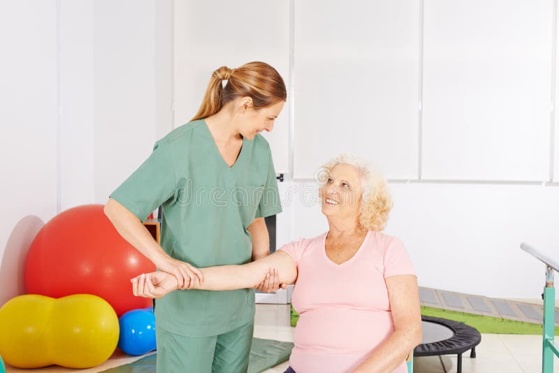 Woman with aching shoulder in physical therapy. Old women with aching shoulder in physical therapy doing exercises royalty free stock image