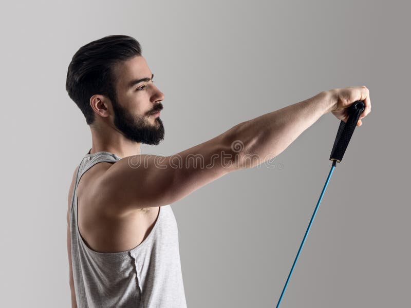 Young athlete in tank top workout with elastic resistance band doing shoulder exercises. Side view of young athlete in tank top workout with elastic resistance stock images