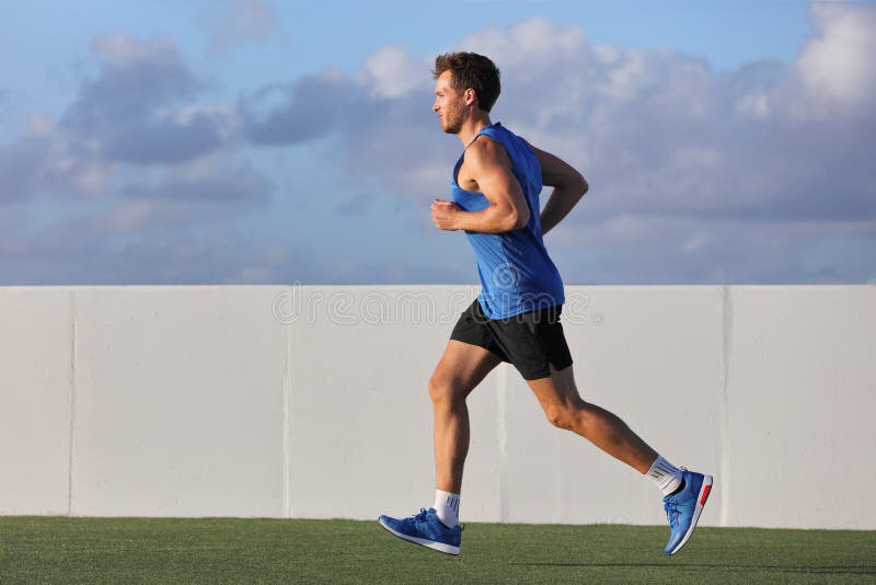 Young man runner running in city park on summer grass outdoors at sunset at outdoor stadium fitness centre. Healthy lifestyle stock images