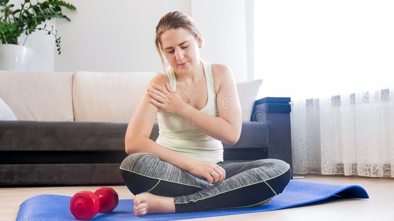 Young woman stopped fitness exercise because of pain in shoulder. Woman stopped fitness exercise because of pain in shoulder royalty free stock photography