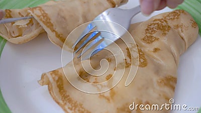 White plate green stripe lie two pancakes Fork knife lay out pancakes. Close up. On a white plate with a green stripe lie two pancakes with sweet syrup. Fork and stock video