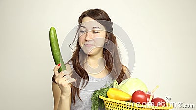 Young woman holding a basket, gets out of the basket of large cucumber and assesses its.  stock video footage